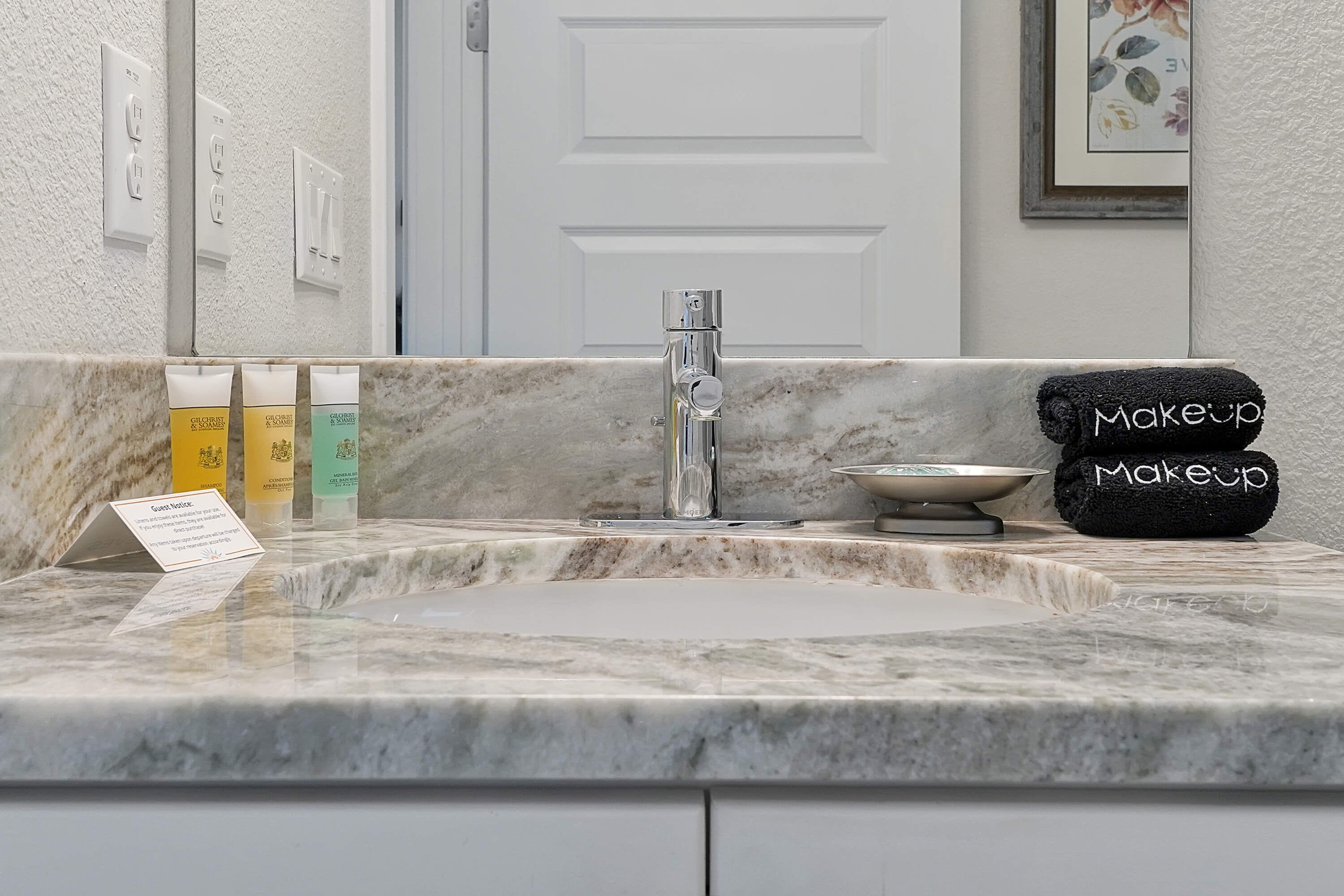 A bathroom with a marble sink, a mirror, and toiletries.
