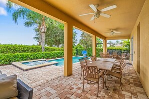 Eine Außenpatio mit Pool, Sitzbereich und Deckenventilatoren.