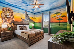 A bedroom with a large mural of a lion, a bed, a nightstand, a lamp, and a ceiling fan. - Astonishing Villa w/ Home Theater at Encore (Kissimmee)