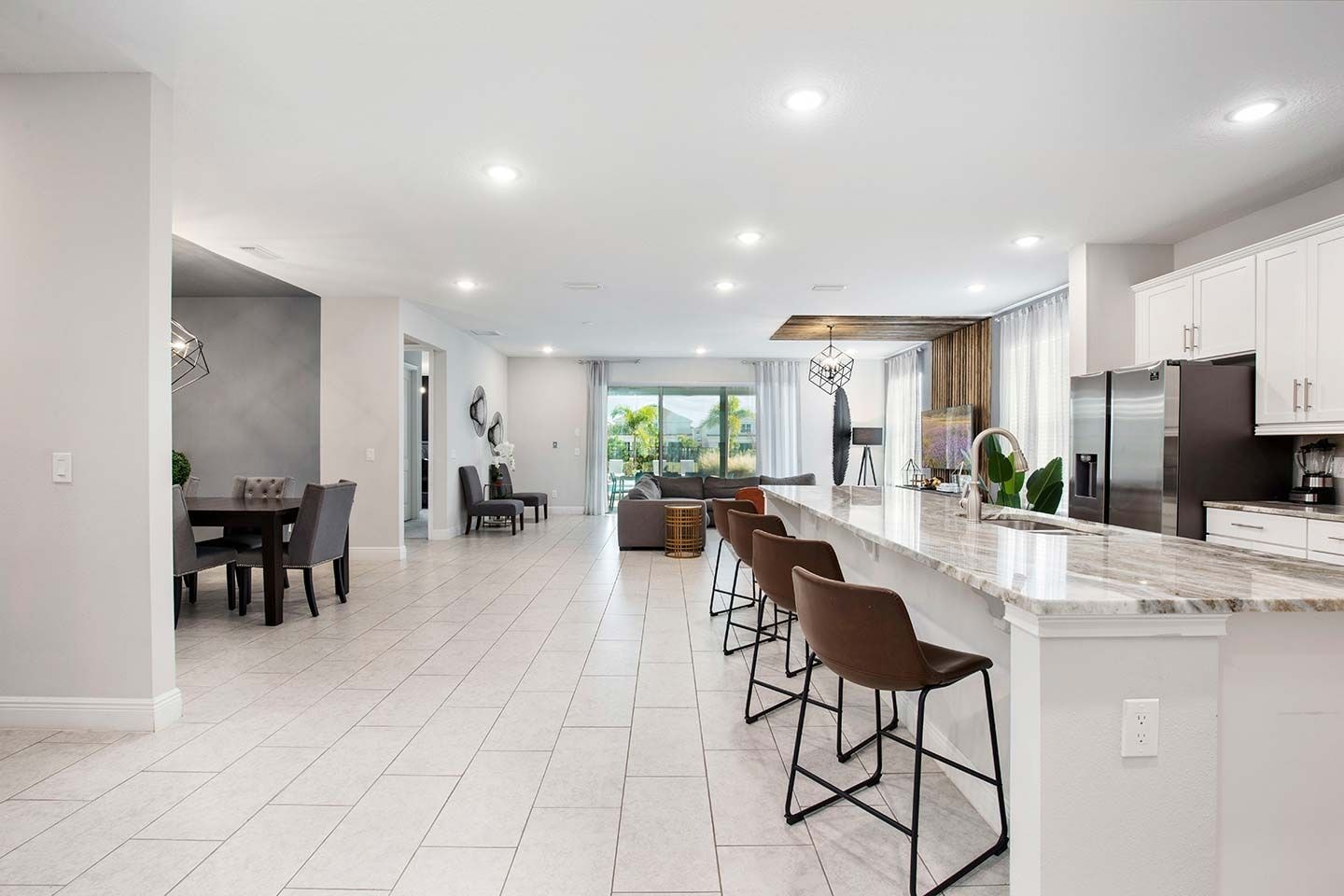 A modern kitchen with a marble island, stainless steel appliances, and a dining area with a dark wood table and chairs.