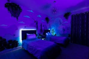 Una habitación con dos camas, una mesita de noche y un mural en la pared con escenas submarinas.
