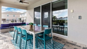 Une terrasse extérieure avec une porte vitrée donnant sur une piscine, une table à manger avec des chaises et un canapé.