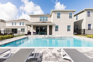 A modern building with a swimming pool, outdoor seating, and a covered patio area. - 10br Encore Villa, 10 Min From Disney Parks (Kissimmee)