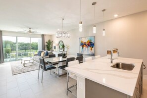 A modern kitchen with a large island, dining area, and a view of the outdoors. - Artistic Townhouse With Games Room at Reunion (Kissimmee)