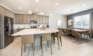 A modern kitchen with a central island, stainless steel appliances, and pendant lighting. - Colorful Villa With Game Room in Encore (Kissimmee)