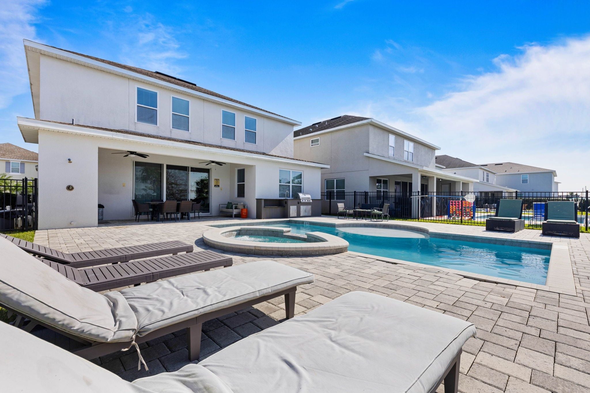 A residential property with a swimming pool, lounge chairs, and a barbecue area.