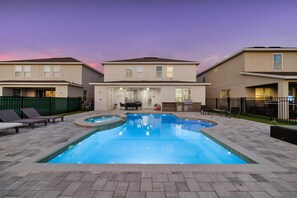 En bostadsbyggnad med en swimmingpool, utomhusmöbler och ett område för grillning.