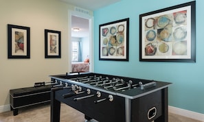 A room with a foosball table, a black sofa, and three framed abstract paintings on the wall. - 10br Encore Villa Pool, Spa & TV Loft (Kissimmee)