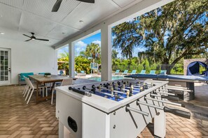 Ein Außenpoolbereich mit Tischfußball, Liegestühlen und einem Basketballkorb.