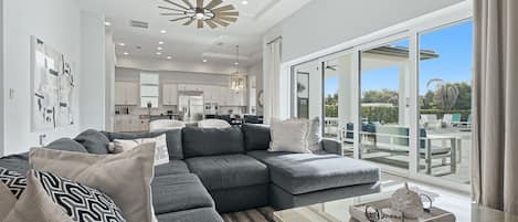 A modern living room with a sectional sofa, a glass coffee table, and a view of the outdoor patio.