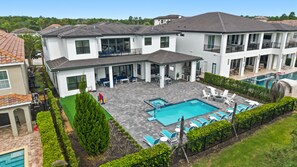 Ein modernes, zweistöckiges Haus mit Swimmingpool, Sitzgelegenheiten im Freien und einem gepflegten Garten.