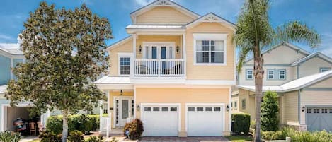 A two-story residential house with a front porch, a garage, and a landscaped front yard.