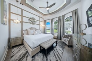 A bedroom with a large bed, a ceiling fan, a desk, and a chair. - Deluxe Mansion With Swim up Bar and Pool Slide at Reunion (Kissimmee)