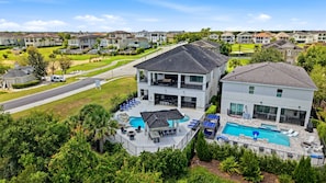 A residential area with two houses, a swimming pool, and a well-maintained lawn. - Deluxe Mansion With Swim up Bar and Pool Slide at Reunion (Kissimmee)