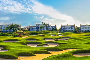 Un parcours de golf avec des bunkers et une rangée de maisons en arrière-plan.