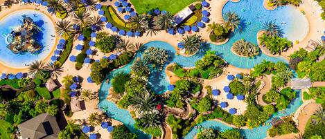 An aerial view of a resort with multiple swimming pools, palm trees, and sun loungers.