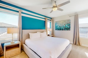 Une chambre d’hôtel avec un grand lit, un ventilateur de plafond, un tableau et une vue sur la ville.