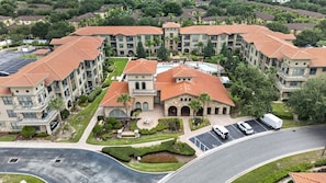 A multi-story hotel with a central courtyard, parking area, and a swimming pool. - Bella Piazza 3BR Retreat Near Orlando Attractions (Davenport)