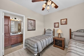 Ein Schlafzimmer mit einem Bett, einem Nachttisch, einer Lampe und einem Deckenventilator.