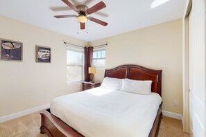 A bedroom with a bed, a ceiling fan, a window with curtains, and two wall-mounted pictures. - Charming 6BR Encore Villa Pool, Spa & Disney Near (Kissimmee)