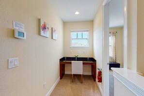 A hallway with a desk, a chair, a fire extinguisher, and a window. - Charming 6BR Encore Villa Pool, Spa & Disney Near (Kissimmee)