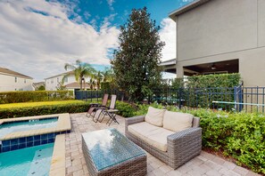 A pool area with a lounge chair, a sofa, and a small table. - Charming 6BR Encore Villa Pool, Spa & Disney Near (Kissimmee)