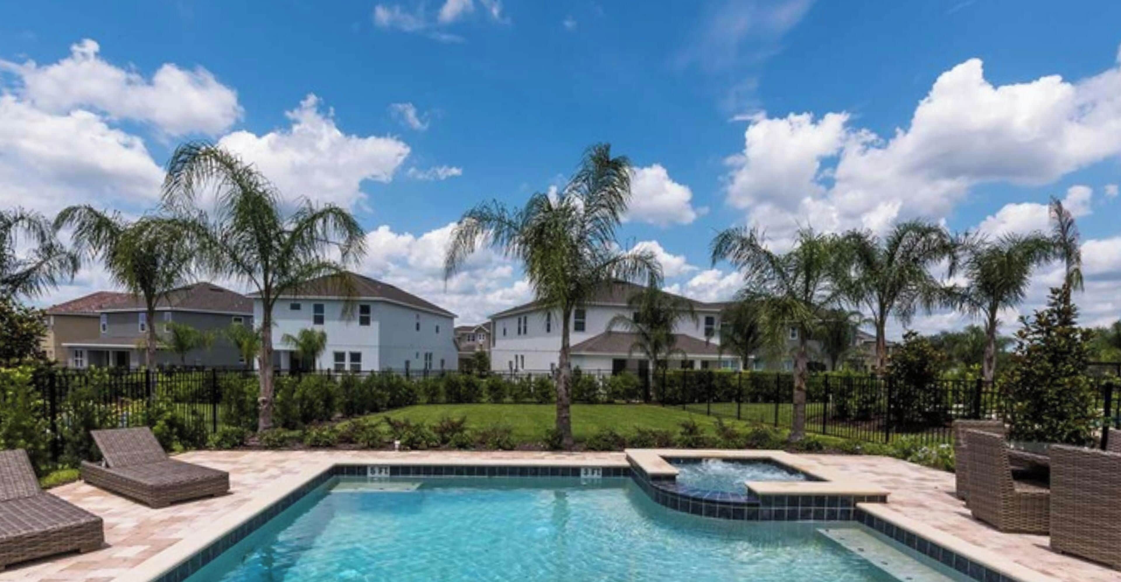 A residential area with a swimming pool, houses, and palm trees.