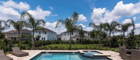 A residential area with a swimming pool, houses, and palm trees.
