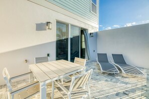A patio with a table and chairs, a glass door, and two lounge chairs. - Bright and Sunny Townhouse With Games Room at Reunion (Kissimmee)