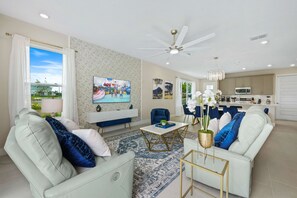 Ein modernes Wohnzimmer mit einer Couch, Sesseln, einem Couchtisch und einem Fernseher.