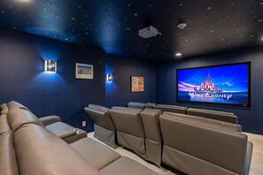 Ein Heimkinozimmer mit großem Flachbildfernseher, hochverstellbaren Ledersesseln und einer Sternenhimmel-Deckenkonstruktion.