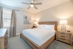Ein Schlafzimmer mit einem Bett, Nachttischen, einem Deckenventilator und einem Fenster mit Vorhängen.