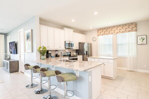 A modern kitchen with white cabinets, stainless steel appliances, and a granite countertop. - Dashing Villa With Games Room at Encore (Kissimmee)