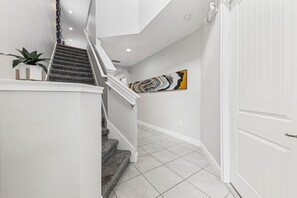 A staircase with a handrail, a potted plant, and a wall-mounted artwork. - Airy House With Private Pool in Encore (Kissimmee)