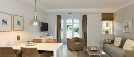 A modern living room with a dining area, a sofa, a coffee table, and a television.