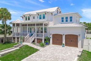A two-story house with a covered porch, a garage, and a well-maintained lawn. - Charming Vacation Retreat just steps from Siesta Key Beach with heated pool. (Siesta Key)