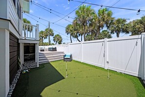 A backyard with artificial grass, a white fence, and a patio area with outdoor furniture. - Charming Vacation Retreat just steps from Siesta Key Beach with heated pool. (Siesta Key)