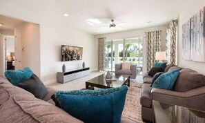 A modern living room with a sofa set, a coffee table, and a TV on a white wall. - Spacious Abode With Spillover Spa in Encore (Kissimmee)