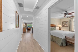 A hotel room with a bed, a desk, a chair, a ceiling fan, and a window with curtains. - The Coastal Inspiration With Private Balcony at Reunion (Kissimmee)
