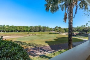 A golf course with a clear sky, palm trees, and a well-maintained lawn. - The Coastal Inspiration With Private Balcony at Reunion (Kissimmee)