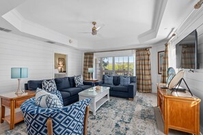 A spacious living room with two sofas, a coffee table, and a television. - The Coastal Inspiration With Private Balcony at Reunion (Kissimmee)