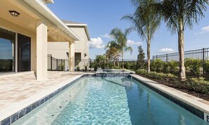 A swimming pool with a clear blue water feature, surrounded by a landscaped garden with palm trees and a fence. - Lively Home With Galactic Themed Bedroom at Encore (Kissimmee)