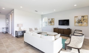 A modern living room with a white sofa, a coffee table, and patterned chairs. - Lively Home With Galactic Themed Bedroom at Encore (Kissimmee)