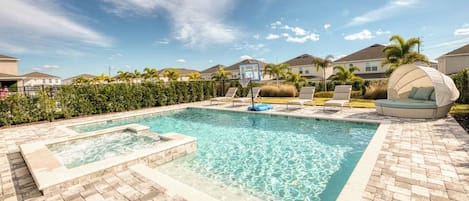 A swimming pool with a hot tub, lounge chairs, and a covered seating area.