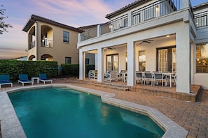 A two-story house with a swimming pool, outdoor seating, and a covered patio area. - Polished Villa With Home Theater at Reunion (Kissimmee)
