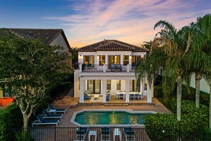 A two-story house with a swimming pool, outdoor seating, and a balcony. - Polished Villa With Home Theater at Reunion (Kissimmee)