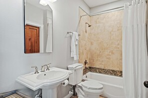 Un baño con ducha, inodoro y dos lavamanos.