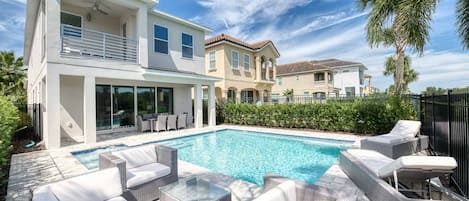 A modern house with a swimming pool, outdoor furniture, and a well-maintained garden.