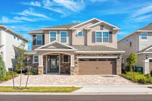 A two-story house with a stone facade, a front garage, and a well-maintained lawn. - Exquisite Home w/ Games Room at Encore (Kissimmee)