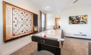 A room with a foosball table, a large Scrabble board, and a television. - Modern Villa With Private Pool in Encore (Kissimmee)